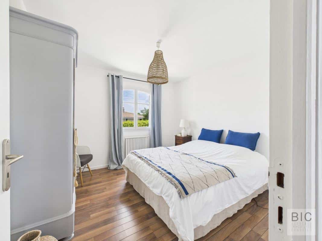 Chambre d'une maison familiale spacieuse à Mérignac, avec lit double et décoration lumineuse.