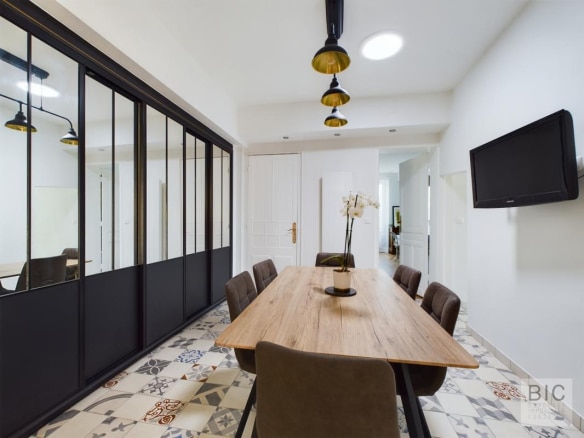 Salle à manger moderne avec table en bois et chaises, éclairage suspendu, murs clairs et décor élégant.