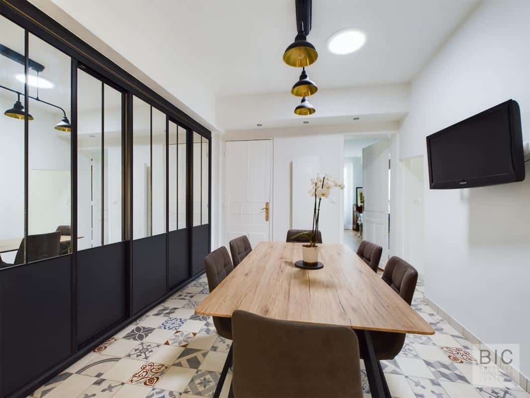Salle à manger d’une maison coloniale Salle à manger moderne avec table en bois et chaises, éclairage suspendu, murs clairs et décor élégant.