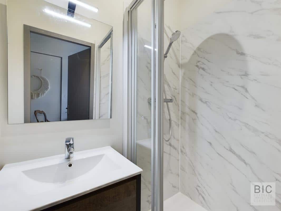 Salle de bain contemporaine Salle de bain moderne avec douche et miroir, murs en marbre blanc.