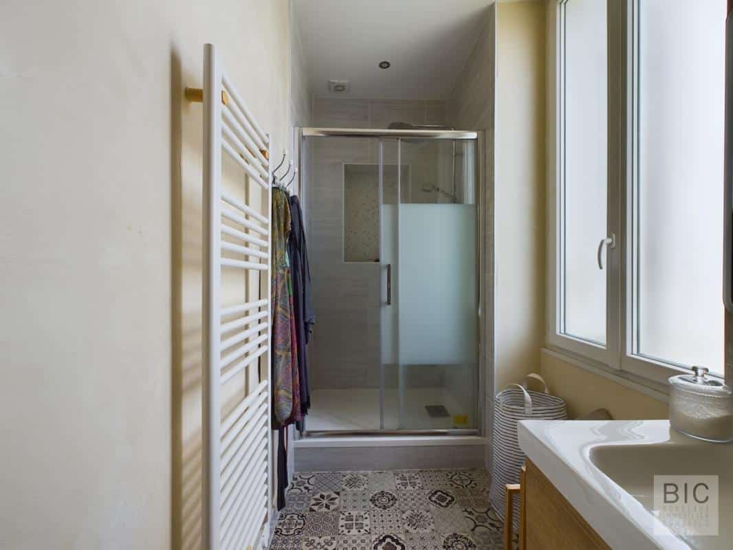 Salle de bain contemporaine Salle de bain moderne avec douche et lavabo, murs clairs et carrelage décoratif.