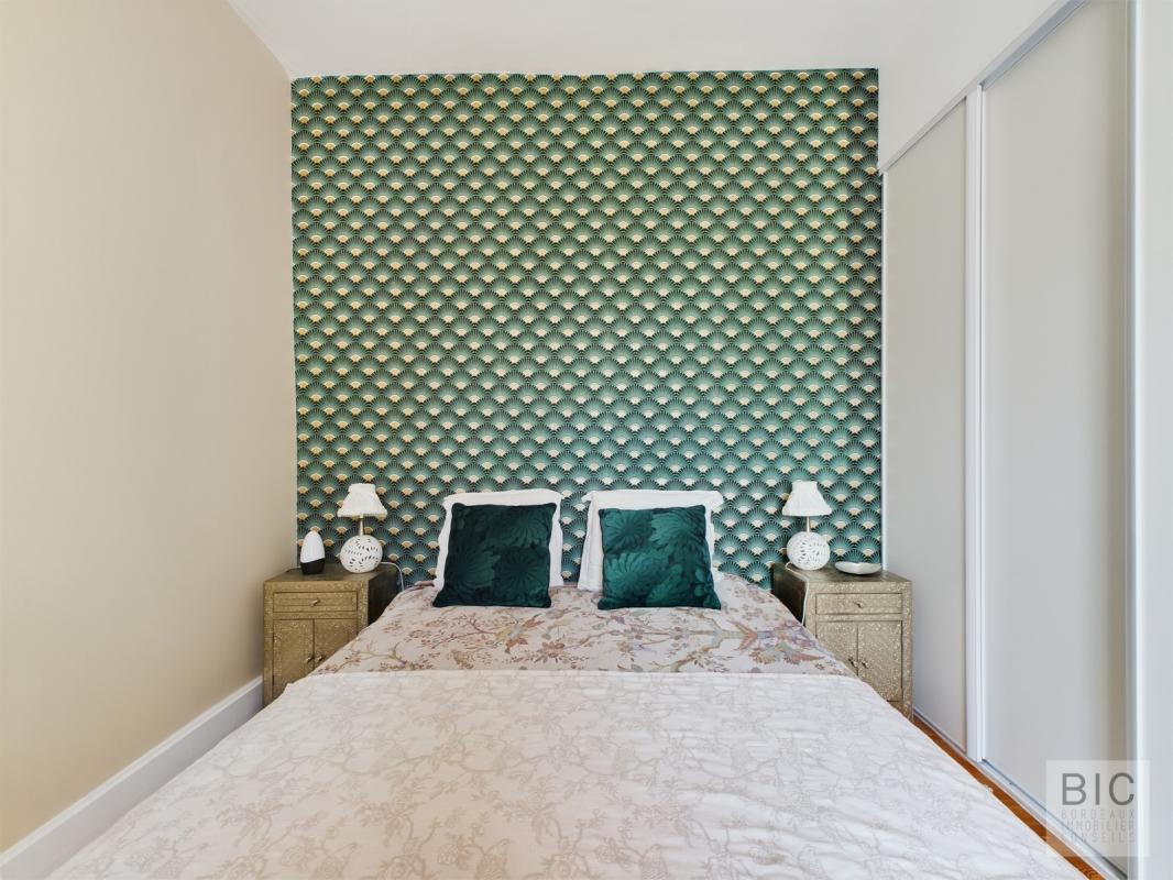 Chambre de maison familiale à Villenave-d’Ornon Chambre d'une maison familiale avec un mur décoré de motifs verts et un lit double.