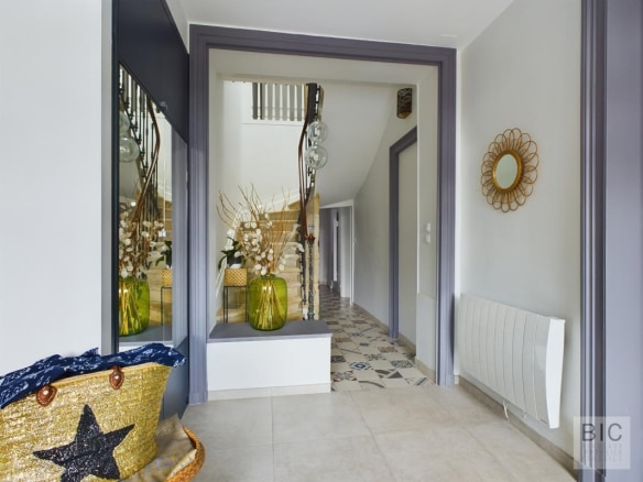 Entrée d'une maison coloniale avec décoration moderne et lumière naturelle.