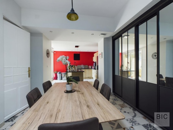 Intérieur d'une maison familiale avec une grande table en bois et des murs rouges.