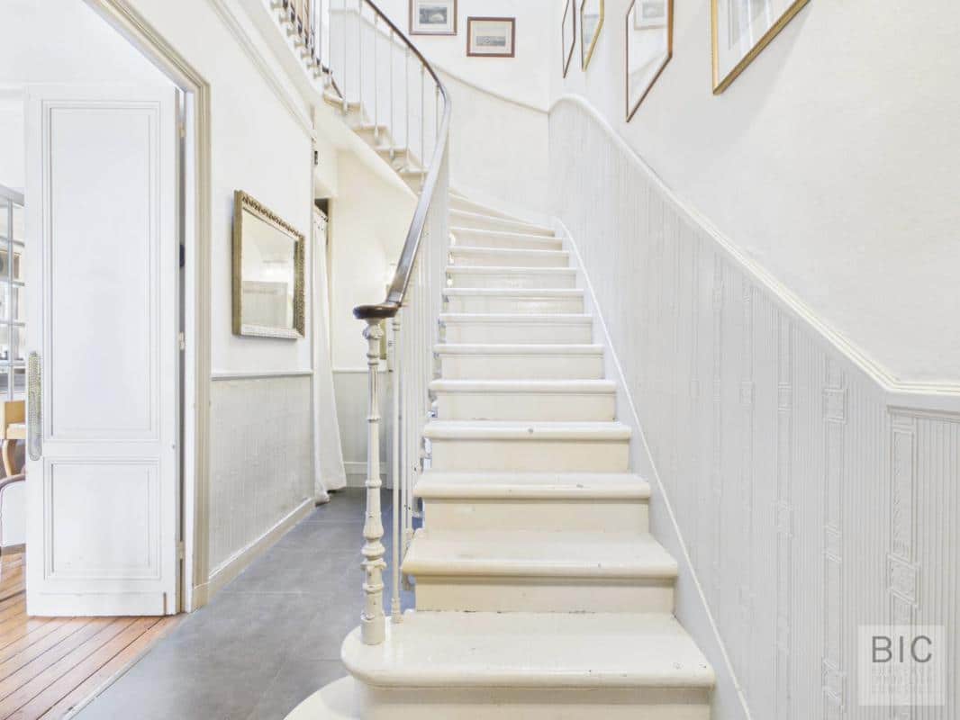 Escalier d’une maison en pierre à Bordeaux Escalier en pierre d'une maison en pierre à Bordeaux, avec des murs blancs et des cadres accrochés.