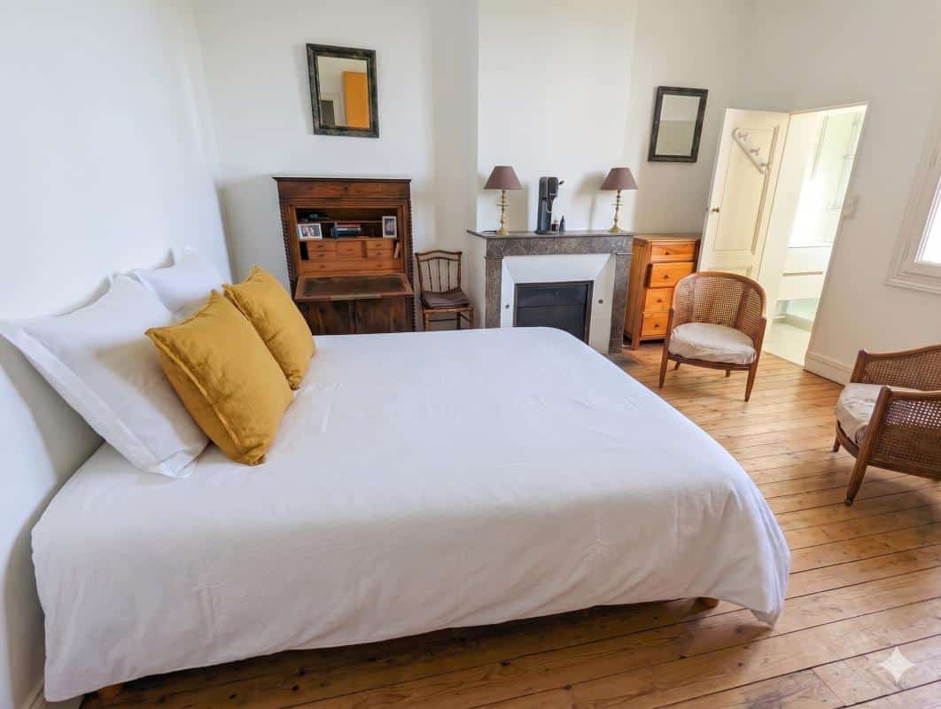 Chambre d’une maison en pierre à Bordeaux Chambre d'une maison en pierre à Bordeaux, avec lit, fauteuils et cheminée