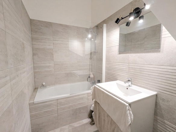 Salle de bain moderne avec baignoire, lavabo et miroir.