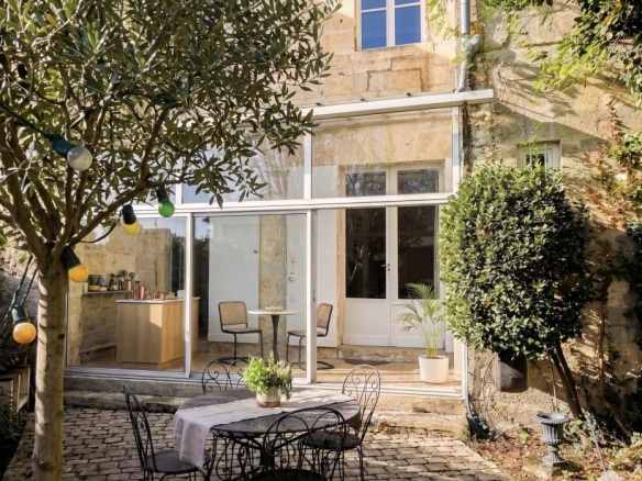 Terrasse d'une maison en pierre avec mobilier de jardin et végétation à Bordeaux.