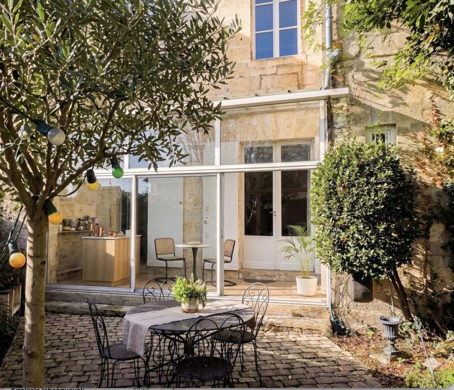 Terrasse d’une maison en pierre à Bordeaux Terrasse d'une maison en pierre avec mobilier de jardin et végétation à Bordeaux.