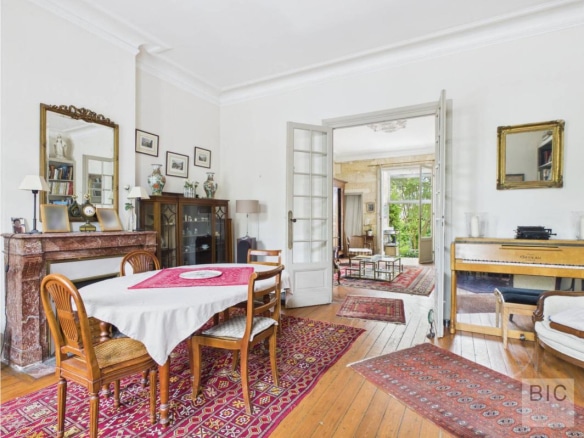 Intérieur d'une maison en pierre avec salon, salle à manger et accès au jardin.