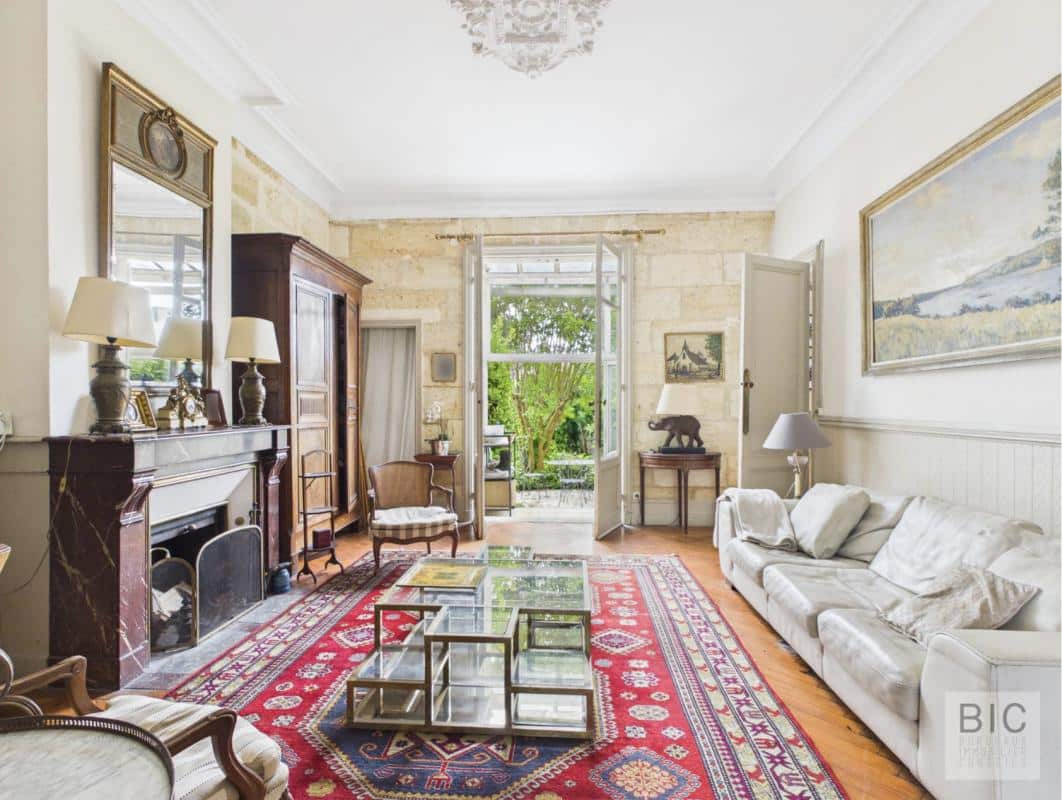 Salon d’une maison en pierre à Bordeaux Intérieur d'une maison en pierre à Bordeaux, avec un salon lumineux, un tapis persan et des meubles anciens.