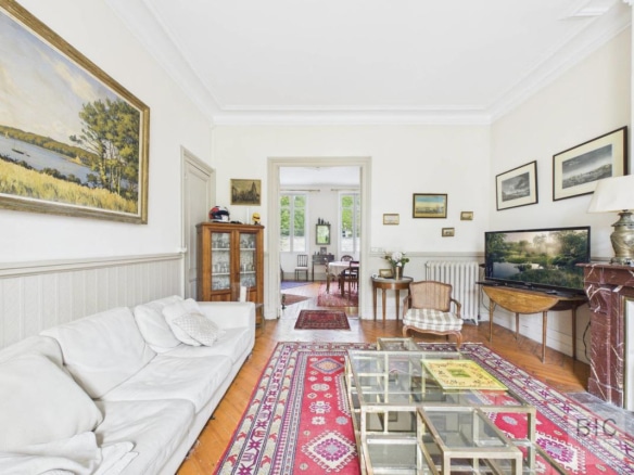 Intérieur d'une maison en pierre à Bordeaux avec salon lumineux, canapé, tableaux et télévision.