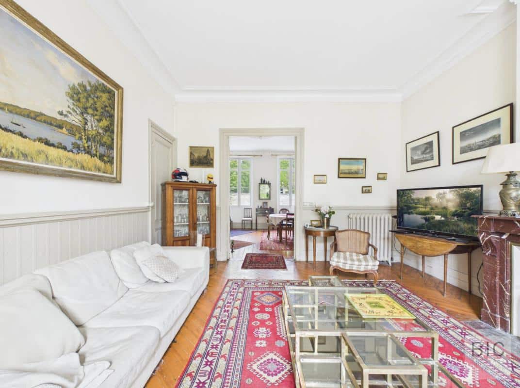 Intérieur d’une maison en pierre à Bordeaux Intérieur d'une maison en pierre à Bordeaux avec salon lumineux, canapé, tableaux et télévision.