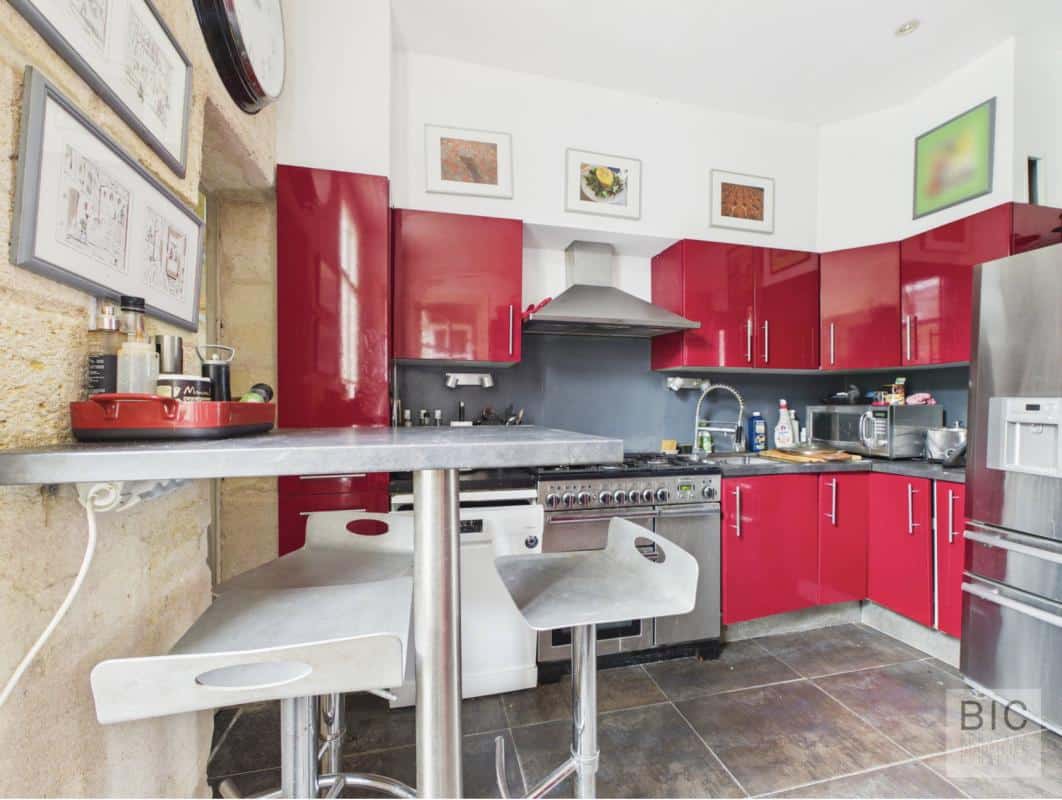 Cuisine de maison en pierre à Bordeaux Cuisine moderne avec meubles rouges et plan de travail en métal dans une maison en pierre à Bordeaux.