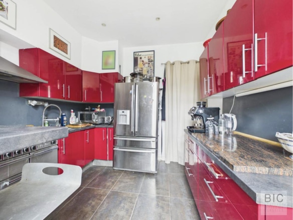 Cuisine moderne avec meubles rouges et plan de travail en pierre dans une maison à Bordeaux.