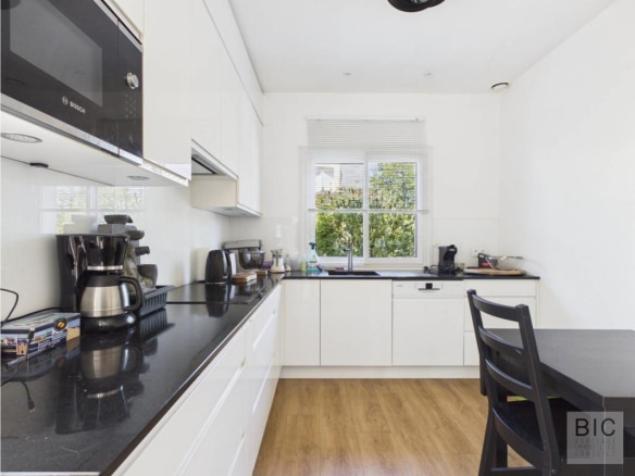 Cuisine moderne avec meubles blancs et plan de travail noir, lumière naturelle à Bordeaux.