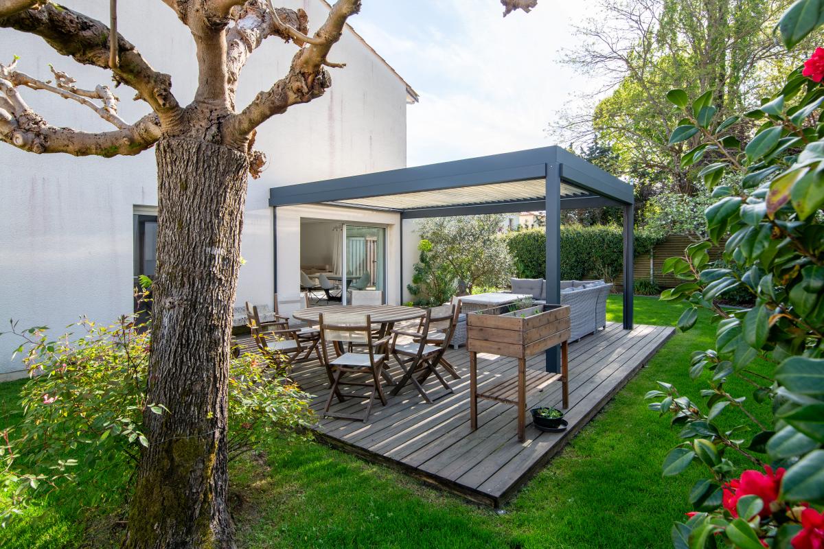 Terrasse de maison à Bordeaux Caudéran Terrasse en bois avec mobilier de jardin dans un jardin verdoyant, maison à Bordeaux Caudéran.