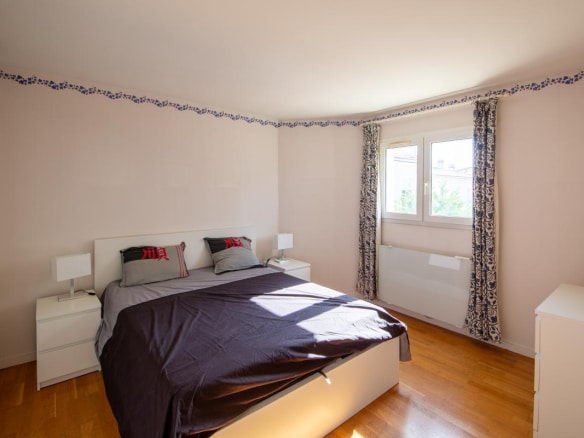 Chambre d'une maison à Bordeaux, avec lit double et fenêtres laissant entrer la lumière.