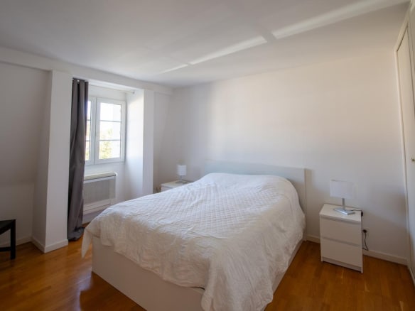 Chambre d'une maison à vendre à Bordeaux, avec un lit double et des meubles modernes.