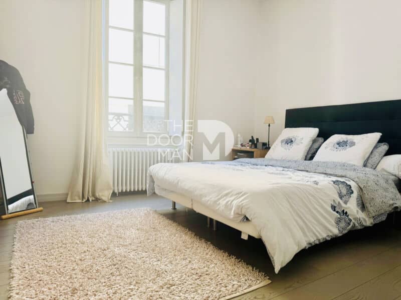 Bedroom in a Laval townhouse with a double bed and mirror.