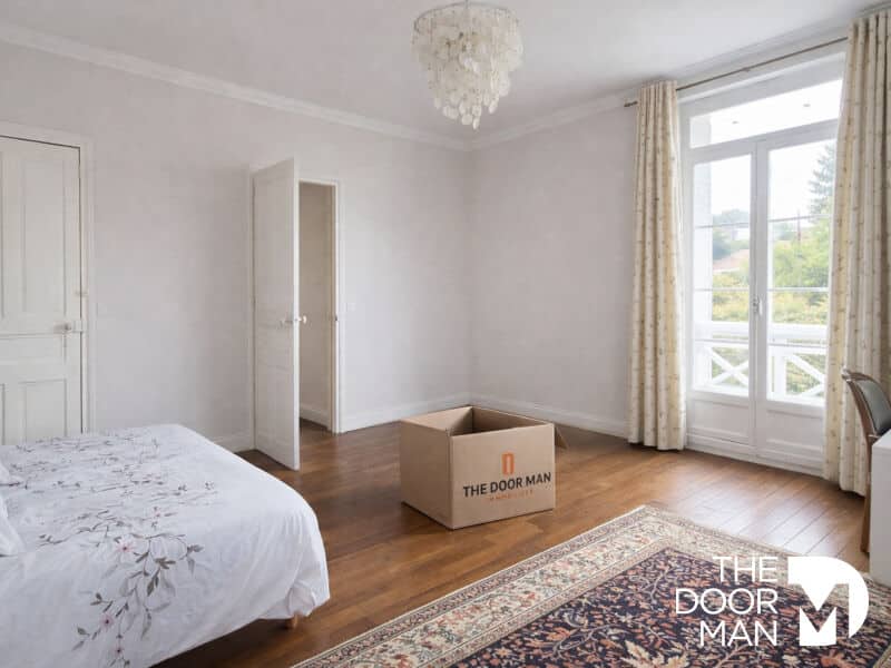 Chambre dans une maison de style meulière Chambre spacieuse avec parquet, fenêtre sur jardin et boîte en carton.
