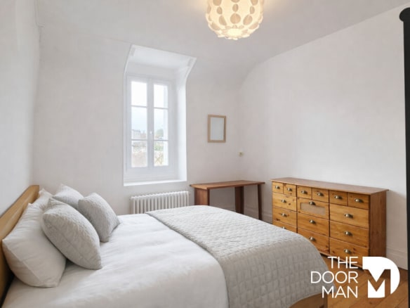 Chambre d'une maison de type meulière à Rambouillet, avec lit, commode en bois et fenêtre.