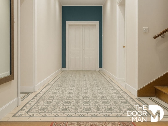 Couloir d'une maison meulière à Rambouillet avec carrelage décoratif et portes blanches.