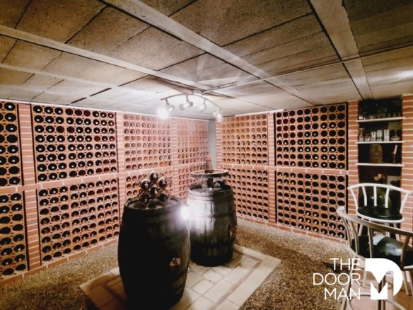 Cave à vin avec étagères en briques et fûts en bois.