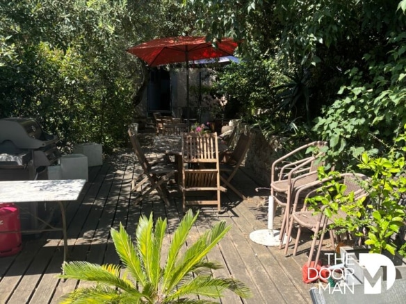 Terrasse en bois avec mobilier de jardin et parasol dans un environnement verdoyant.