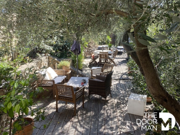 Terrasse en bois avec chaises et tables, entourée de verdure à Grimaud.