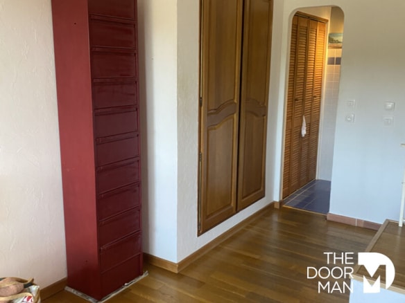 Intérieur d'une maison à Grimaud avec un meuble de rangement rouge et des murs clairs.