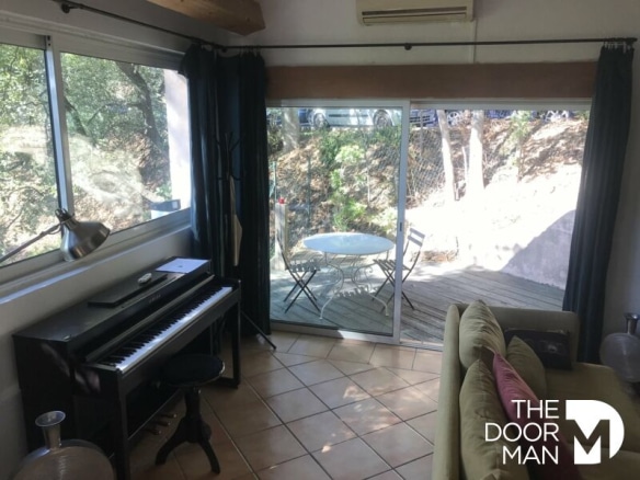 Intérieur d'une maison à Grimaud avec un piano et une terrasse ensoleillée.
