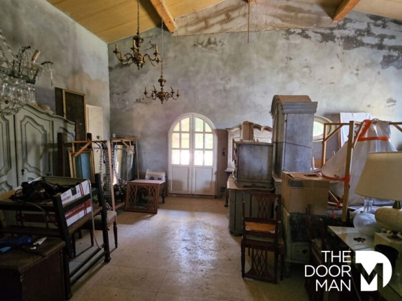 Intérieur d'une propriété ancienne en cours de rénovation avec des meubles et des poutres apparentes.