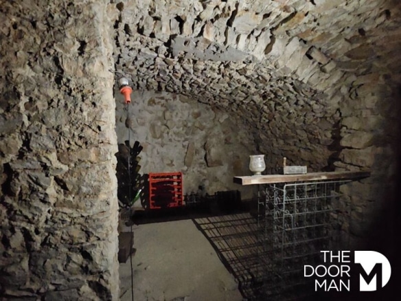 Cave en pierre avec voûte, éclairage et éléments de rangement.
