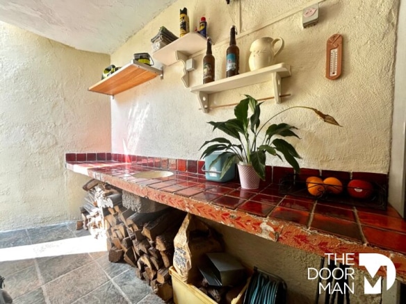 Interior of a house with a tiled bar and shelves, lit by natural light.
