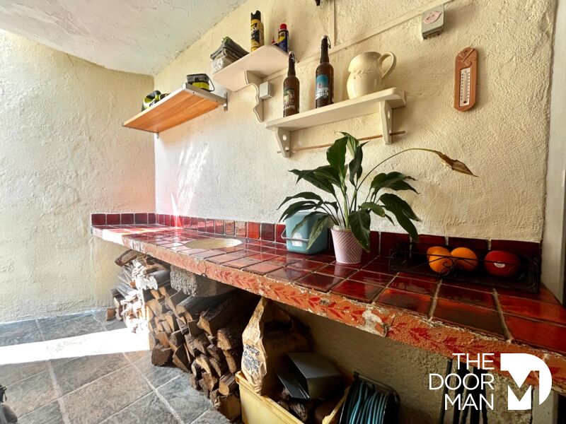 Interior of a house in Le Lavandou Interior of a house with a tiled bar and shelves, lit by natural light.