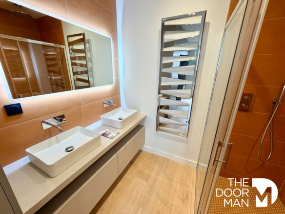 Salle de bain moderne avec double vasque et douche à l'italienne dans un appartement rénové.
