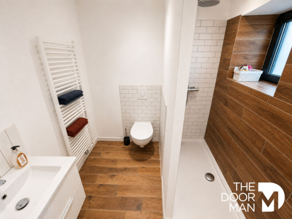 Modern bathroom with shower, toilet and sink, light walls and wooden elements.