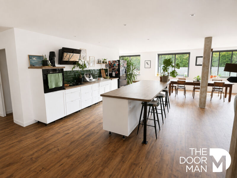 Interior of a modern house with open kitchen and dining room, natural lighting.