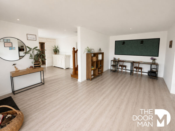 Interior of a spacious house with light-colored flooring and wooden furniture.