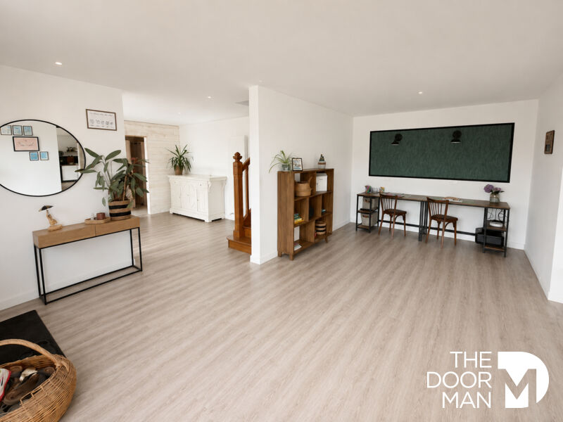 Interior of a spacious house with light-colored flooring and wooden furniture.