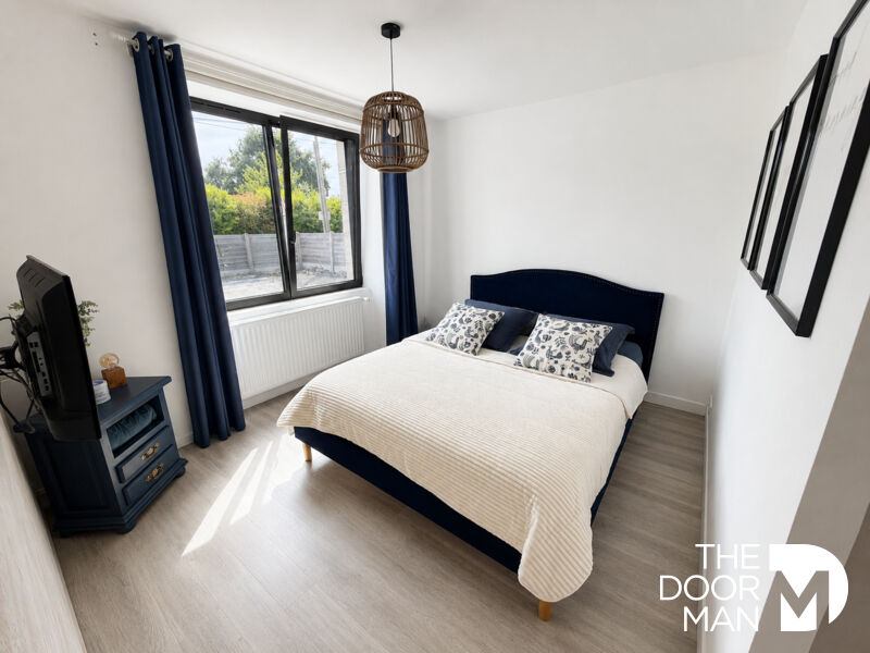 Room with double bed, television and windows letting in natural light.