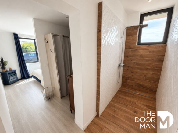 Modern bathroom with shower and bedroom nearby in a house in Matignon.