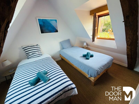 Room with two beds, stone walls, windows open to the outside.