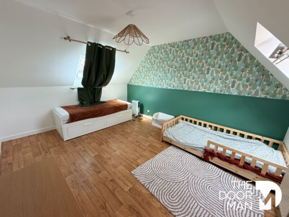 Spacious room with green walls and wood decor, equipped with beds and storage space.