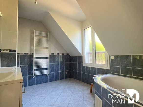 Spacious bathroom with bathtub and tiled floor, window overlooking the outside.
