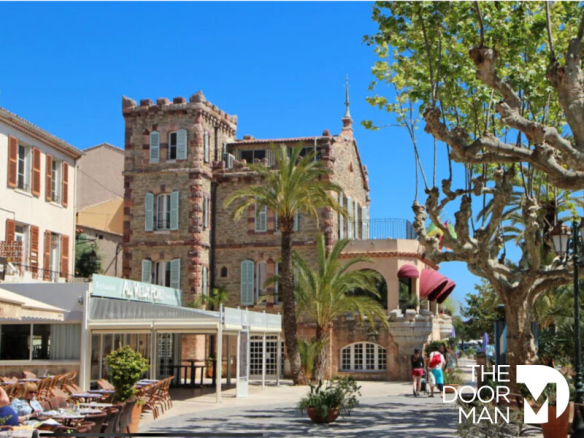 Immeuble à vendre au Lavandou, façade en pierre avec palmier et terrasse au rez-de-chaussée.