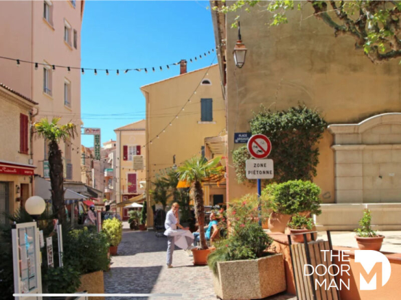 Rue piétonne au Lavandou avec des bâtiments et des terrasses de café.