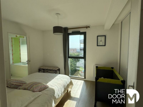 Room in a duplex in Arcachon with bed and view of the outside.