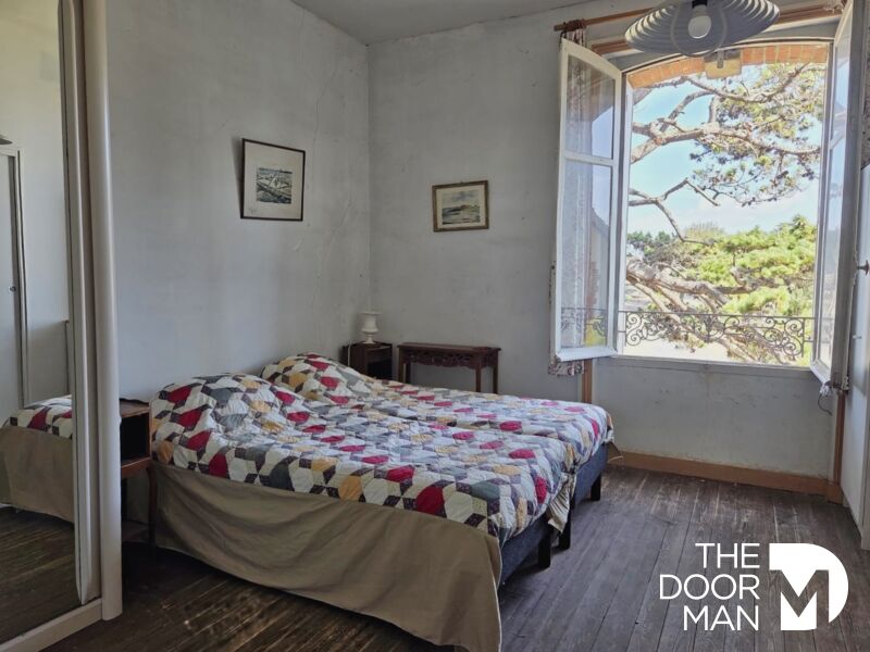 Chambre de l’appartement à Mesquer Chambre d'appartement avec lit double et fenêtre donnant sur un paysage.
